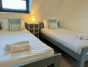 Dos camas individuales en una habitación con ventana. en Granville Lookout - 2 bed Apt, en Ilfracombe