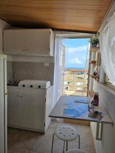 een keuken met een tafel en uitzicht op de oceaan bij Regina Elena Apartment in Marzamemi