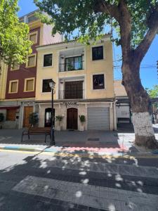 a building with a tree in front of it at Almendra B Vitalba Apartments in Lanjarón