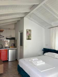 a bedroom with a white bed and a kitchen at Guesthouse Mance in Ksamil