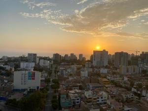a city skyline with the sun setting in the distance at Lindo depa centrico en Barranco in Lima