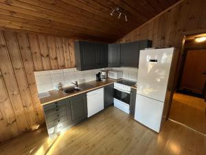 a kitchen with a white refrigerator and wooden walls at Haglebu Turistheim in Haglebu