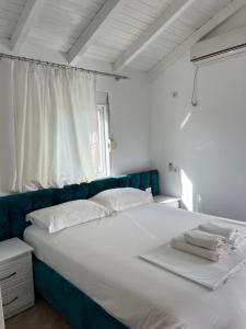 a bedroom with a large white bed with a blue headboard at Guesthouse Mance in Ksamil