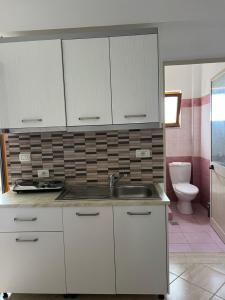 a white kitchen with a sink and a toilet at Guesthouse Mance in Ksamil
