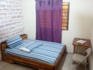 a bed in a room with a purple curtain at Hotel TK d'Or in Kpodji
