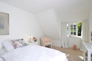 a white bedroom with a white bed and a chair at Kairem Ingiwai 22c in Keitum