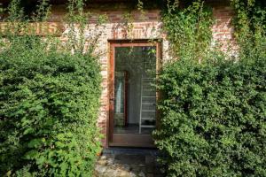 a brick house with a door and some bushes at Barque de Furnes in Ieper
