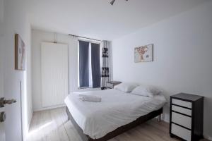 ein weißes Schlafzimmer mit einem Bett und einem Fenster in der Unterkunft Le Lagon Parking Un Séjour à Part in Longeville-lès-Metz