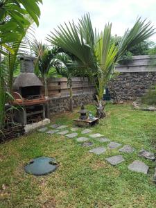 een tuin met een stenen muur en een pizza-oven bij Appartement st leu Vill'Alizoé in Entre-Deux