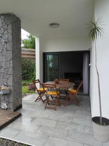 een patio met een houten tafel en stoelen bij Appartement st leu Vill'Alizoé in Entre-Deux