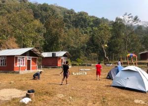 grupa ludzi stojących w polu z namiotami w obiekcie Miknaon River Retreat w mieście Pedong