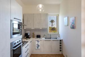 a kitchen with white cabinets and a sink and a window at Breathtaking View - IsulaTravel in Marina di Modica +12 photos