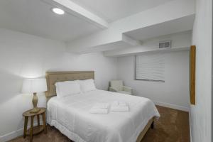 Un dormitorio blanco con una cama y una silla. en Touchdown Airport to Downtown at the Rose Garden, en Salt Lake City