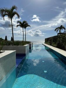 a swimming pool next to the ocean with palm trees at Studio completo Beach Class Salvador - Ondina - Circuito Carnaval in Salvador