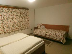 a bedroom with two beds and a window with a curtain at Chaloupka Bernartička in Boršov