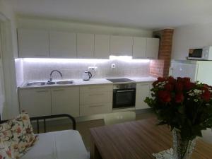 a kitchen with white cabinets and a table with a vase of roses at Chaloupka Bernartička in Boršov