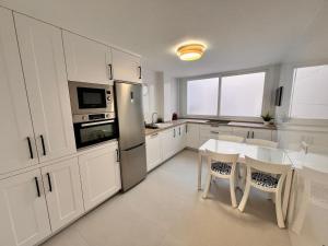 Una cocina con gabinetes blancos y una mesa con sillas. en Victoria Centro 34, en Puerto Real 23 fotos más