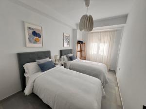 Dos camas en una habitación con paredes blancas. en Victoria Centro 34, en Puerto Real