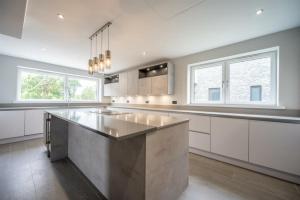 a large kitchen with white cabinets and a stainless steel island at Modern 5 Bedroom Luxury Home with Sea Views and Hot Tub in North Hayling +20 photos