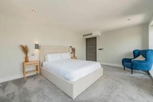 a bedroom with a white bed and a blue chair at Modern 5 Bedroom Luxury Home with Sea Views and Hot Tub in North Hayling