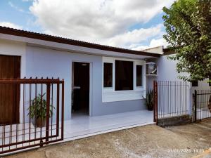 a white house with a gate in front of it at Casa térrea, aos pés do Cristo! in Encantado