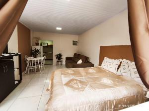 a bedroom with a large bed and a living room at Casa térrea, aos pés do Cristo! in Encantado