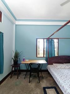 a room with a table and a bed and a table and chair at Anita Homestay in Silchar