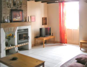 a living room with a television and a fireplace at Villa charmante à Issac avec piscine privée in Issac