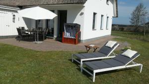 a patio with two chairs and a table with an umbrella at Haus an der Eiche in Wieck