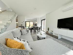 Una sala de estar con un sofá y un televisor. en Casa do Cruzeiro - BY SCH, en Foz do Arelho