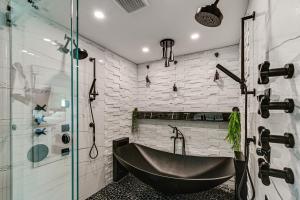 a bathroom with a black tub and a glass shower at 1 Mi to Bonita Beach Park Chic Canal-Front Home! in Bonita Springs +19 photos