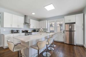 una cucina con armadi bianchi e una grande isola con sgabelli da bar di Luxe Beach Estate - 4 Bedrooms and 3 Bathrooms ad Atlantic City