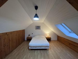 a bedroom with a bed and a window in a attic at Gîte Paisible à la Campagne pour 5 Personnes in Spézet +3 photos