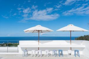 two white tables and chairs with umbrellas on the beach at Bagus in Nakijin