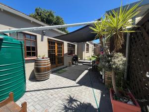 ein Haus mit einem Fass und einer Terrasse mit Pflanzen in der Unterkunft Charming Garden Cottage in Gqeberha