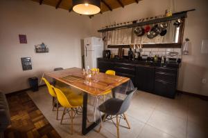 a kitchen with a wooden table and yellow chairs at Refúgio de Lavras in Ouro Preto