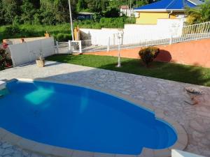a blue swimming pool in a yard with a stone patio at Joli bas-de-villa in Les Abymes