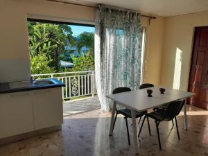 a kitchen with a table and chairs and a large window at Joli bas-de-villa in Les Abymes