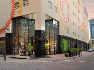 a large building with glass windows on a street at ONOMO Hotel Johannesburg Sandton in Johannesburg