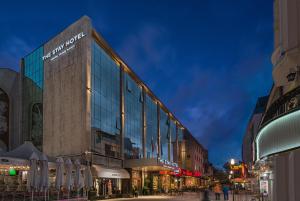 a large glass building on a city street at night at The Stay by Aston Hotel Central Square - Free Compliments - Free Wi-Fi - TOP LOCATION - Nearby Paid Parking in Plovdiv