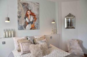 a bedroom with a bed and a painting on the wall at Chambres d'Hôtes & SPA Le Chat Chez Qui j'Habite in Saint-Aubin-sur-Mer