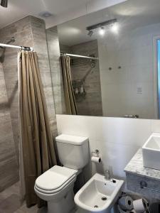 a bathroom with a white toilet and a sink at Departamento de categoria frente al mar in Monte Hermoso