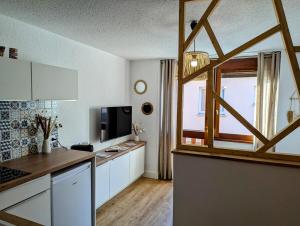 a kitchen with white cabinets and a large window at Studio le Cosy - Bourgoin Centre in Bourgoin