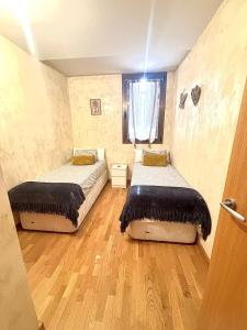 two beds in a room with wooden floors and a window at APARTAMENTO L AÜT in Pla de l'Ermita