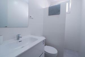 a white bathroom with a toilet and a sink at Habitación en casa compartida "Al-Mariya" in Almería +4 photos