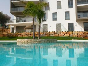 a palm tree in a swimming pool in front of a building at Oasis by Templesuites - Praia da Rocha in Portimão