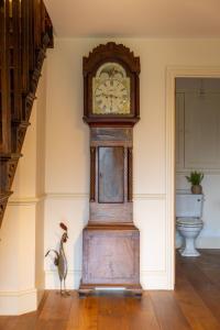 a grandfather clock in the corner of a room at H Oxencombe Farm House in Newton Abbot