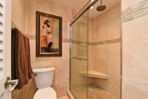 a bathroom with a toilet and a glass shower at Top Floor Penthouse at The Mahana in Lahaina +12 photos