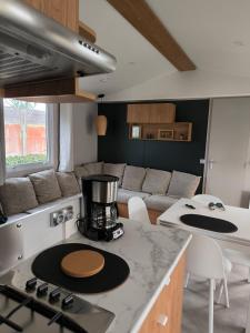 Il dispose d'une cuisine et d'un salon avec une cuisinière et un canapé. dans l'établissement mobil home luminosa 6pers tout équipé 3ch, à Saint-Jean-de-Monts
