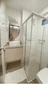 a white bathroom with a sink and a shower at Lindo Apartamento no Centro de Porto de Galinhas in Porto De Galinhas